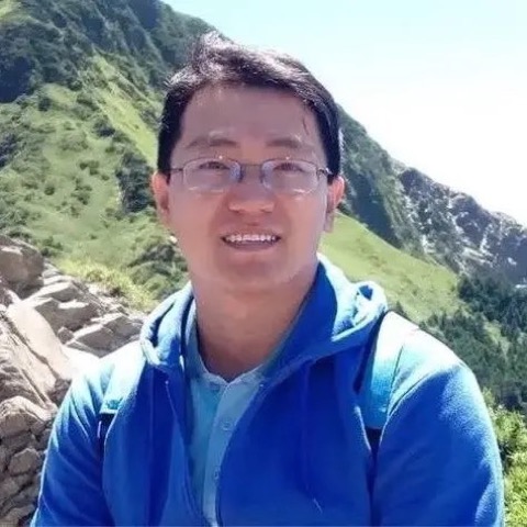 老王在山稜線前的側身照，背景是綠色山坡